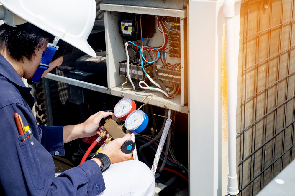 View of an HVAC technician using gauges to adjust the pressure of an air conditioning unit during maintenance.