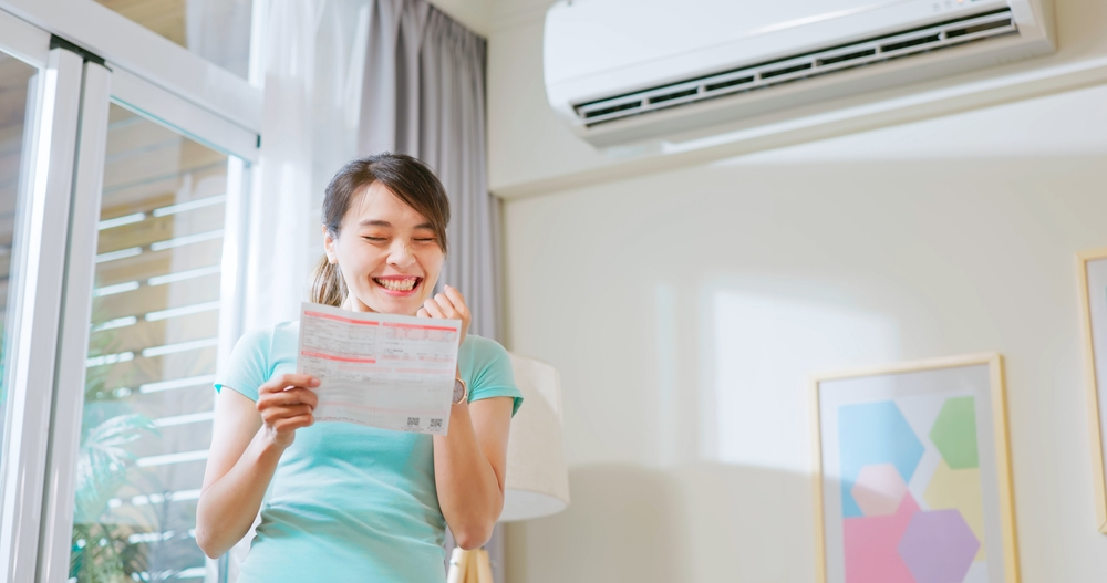 A view of a smiling woman, she celebrates energy bill savings after upgrading to a more efficient AC system.