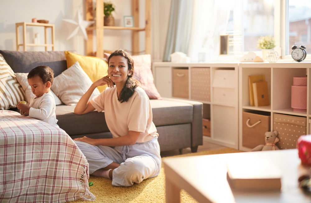 A mother sitting and babysitting her son in the living room.