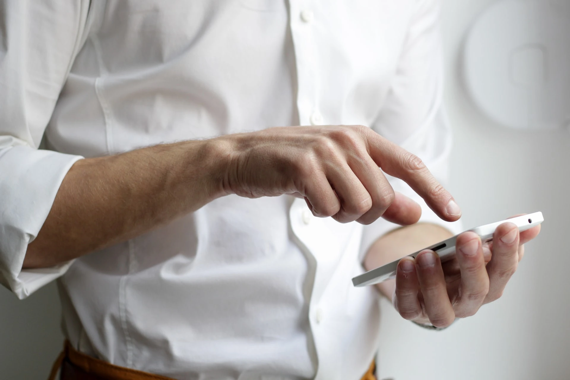 A close-up image of a man's hands holding a smartphone, his fingers poised over the keyboard.