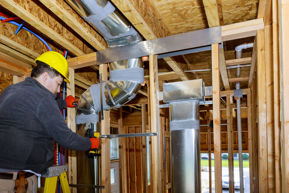 A view of a technician at work, ductwork is being replaced as part of an AC system upgrade in a home under construction.
