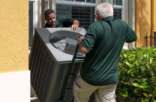 Image of Filterbuy technicians carefully transferring a new air conditioner as a replacement in a Florida home.