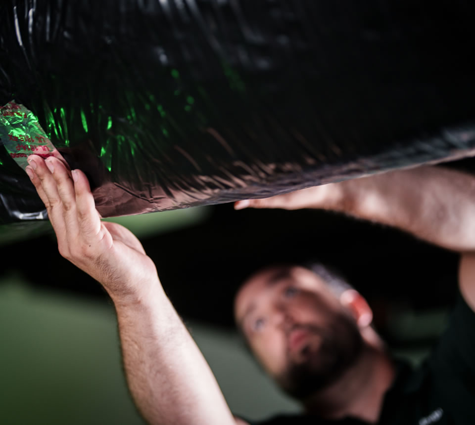 A view of a technician inspecting and sealing HVAC ductwork for proper airflow efficiency.
