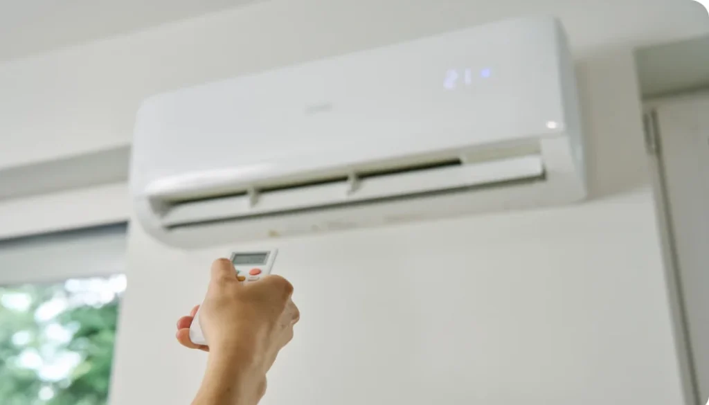 an image of a person using a remote control to operate a home air conditioner unit