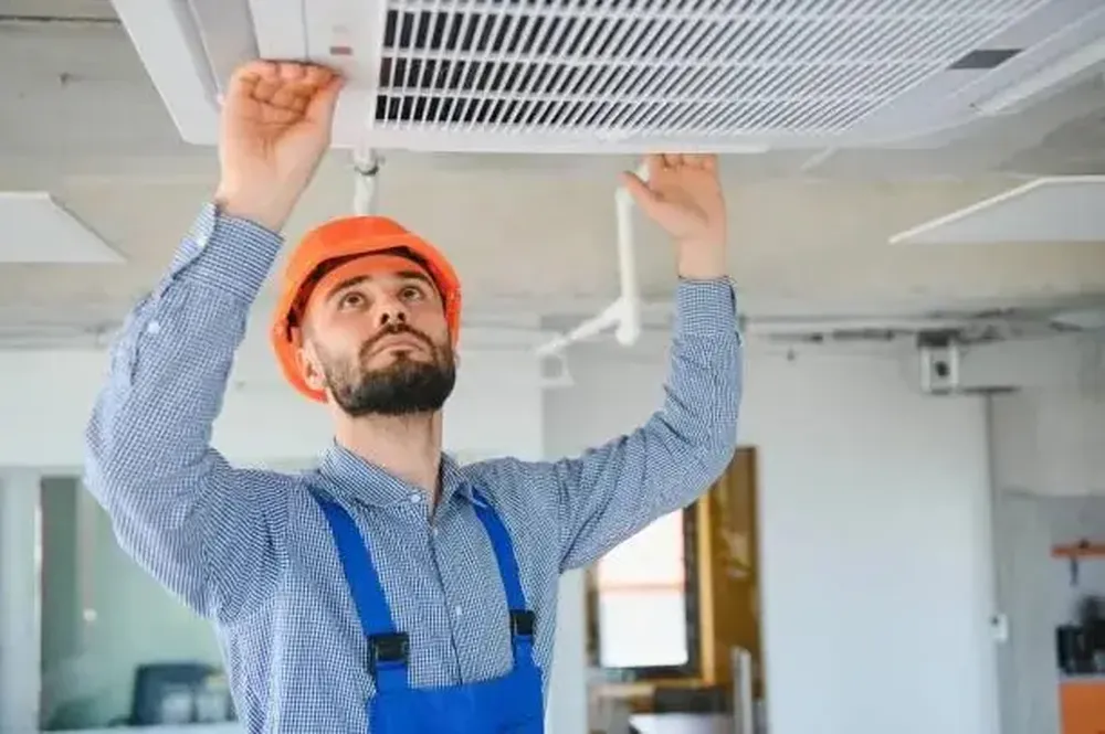 An image of an HVAC technician inspecting a ceiling-mounted air conditioner, showing potential causes for the AC to stop working.