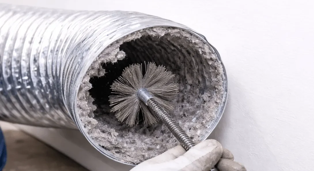 View of dryer duct cleaning in progress using a rotary brush to remove lint buildup from a metal dryer vent, improving airflow and reducing fire risk.
