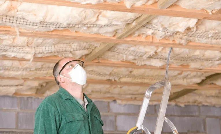 Home attic insulation installation with technician inspecting spray foam insulation for better energy efficiency and comfort